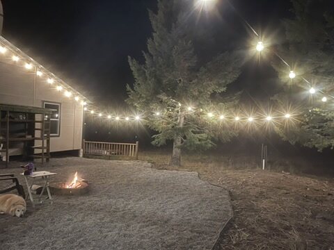Fire pit glowing under string lights once the sky has gone dark