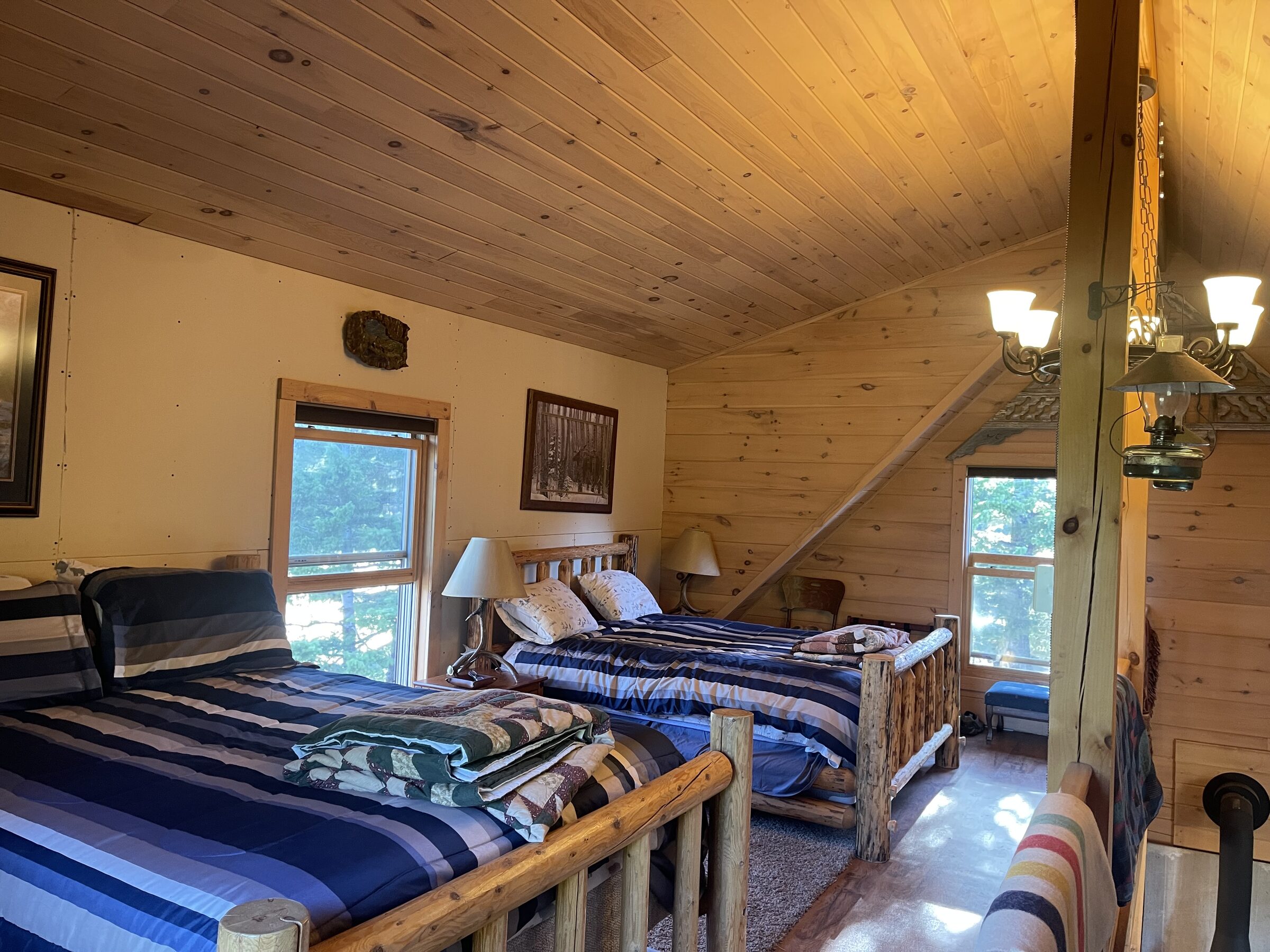 The loft in the Main Cabin at Sweetwater Ranch — a vaulted knotty-pine ceiling over two log-frame beds