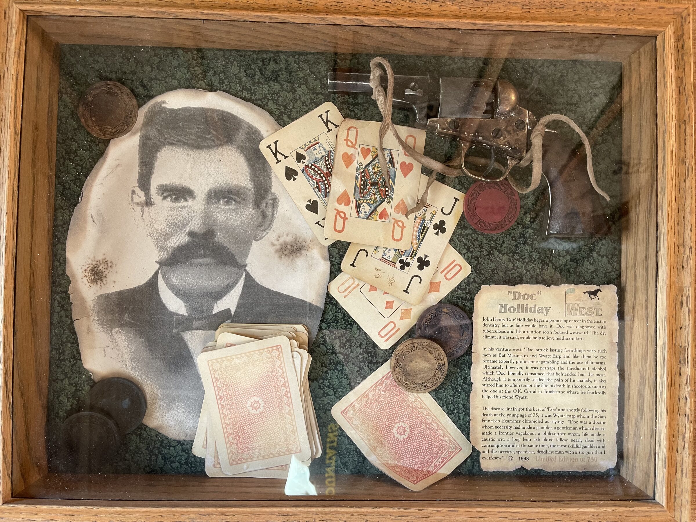 A framed shadowbox of Doc Holliday memorabilia — a sepia portrait, antique playing cards and a small revolver — that gives the suite its name