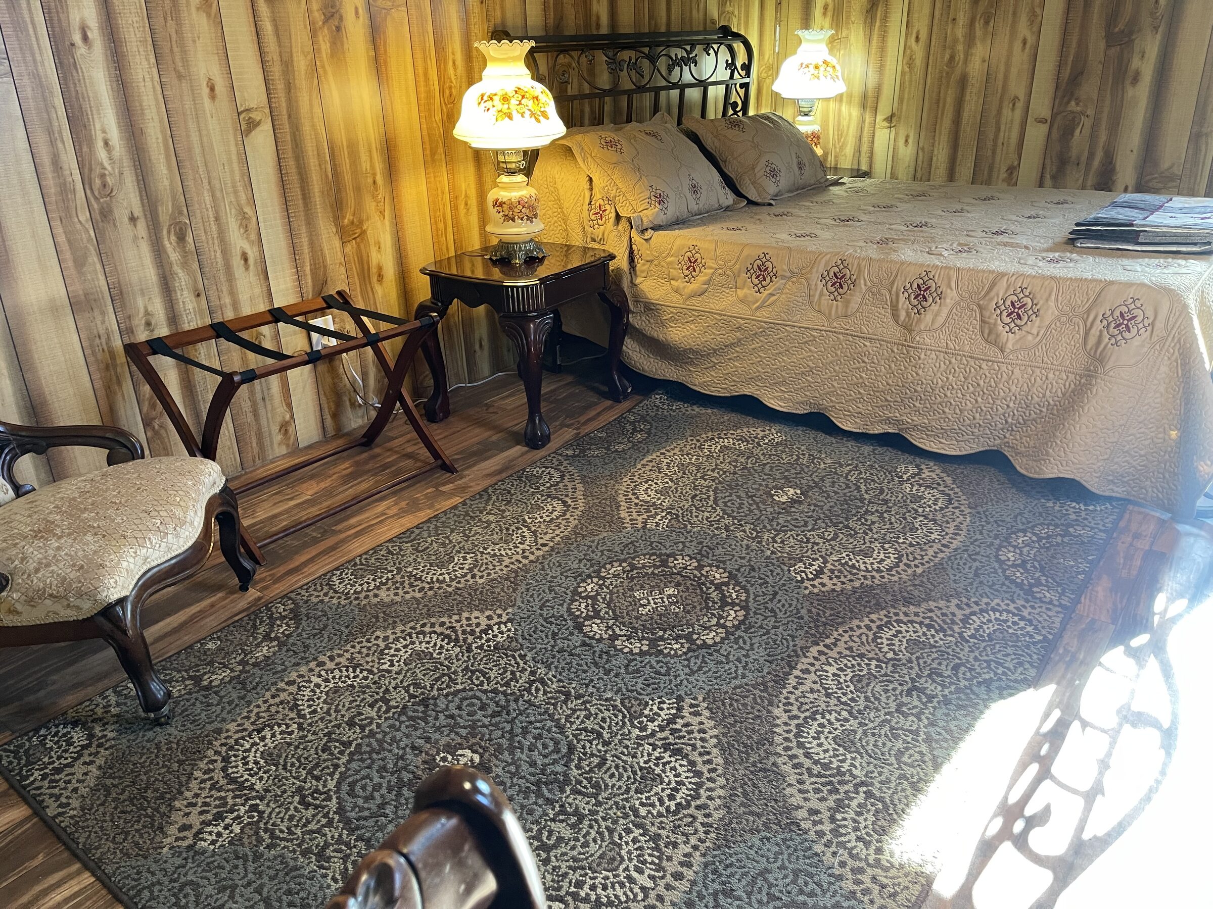 The Doc Holliday Suite within the Whiskey Ridge Boarding House at Sweetwater Ranch — a bed with an antique hurricane lamp beside it