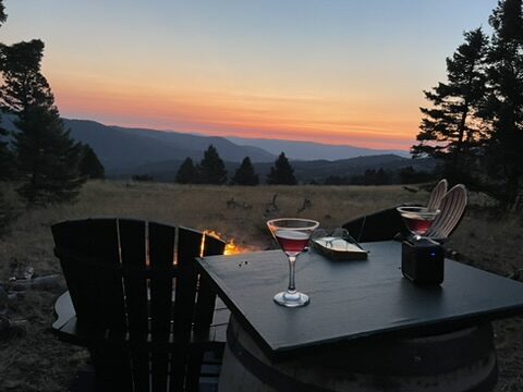 Two cocktails on a table beside the fire pit at sunset