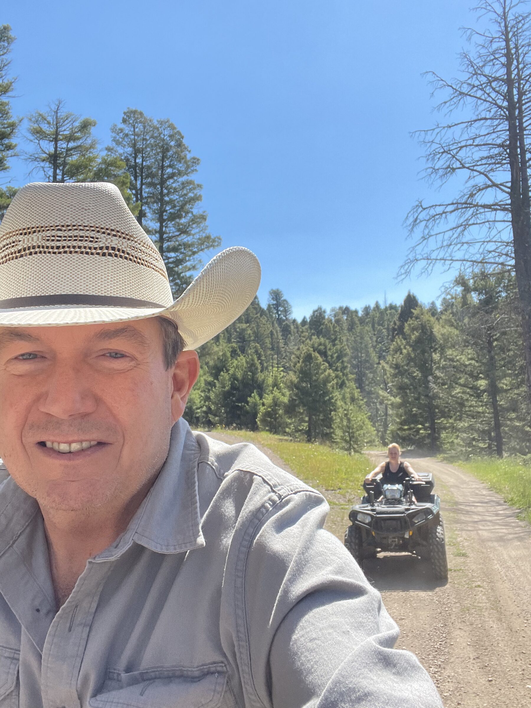 Terry L. Fossum and his wife on an ATV on the forest roads at Sweetwater Ranch at golden hour