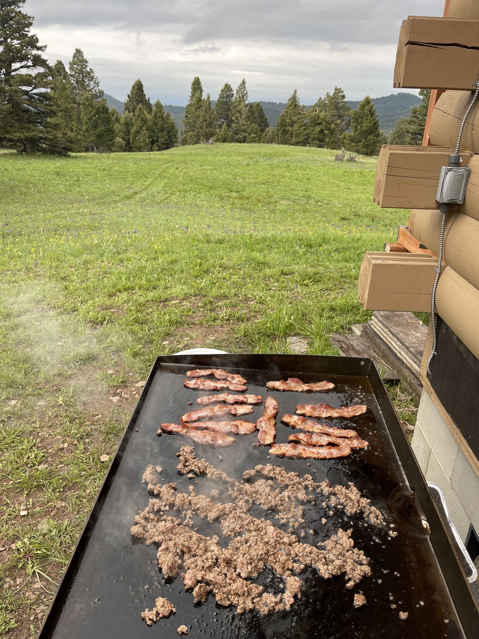 A flat-top griddle cooking outdoors with the open mountain range beyond, just outside the Main Cabin at Sweetwater Ranch