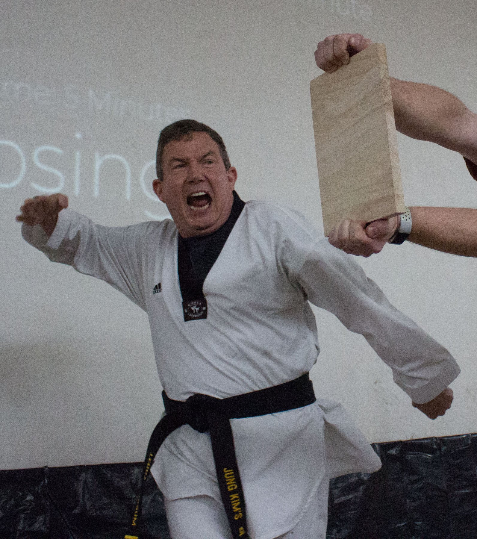 Terry L. Fossum in his black belt uniform, mid-strike, breaking a board
