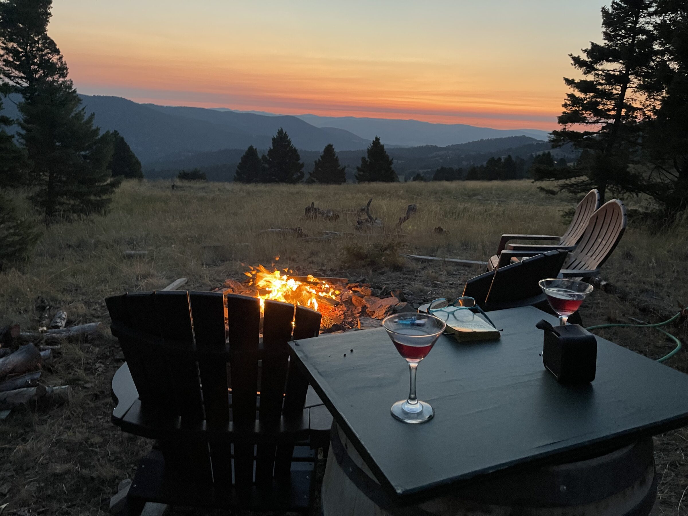 A cocktail glass held up against the setting sun over the mountain ranges