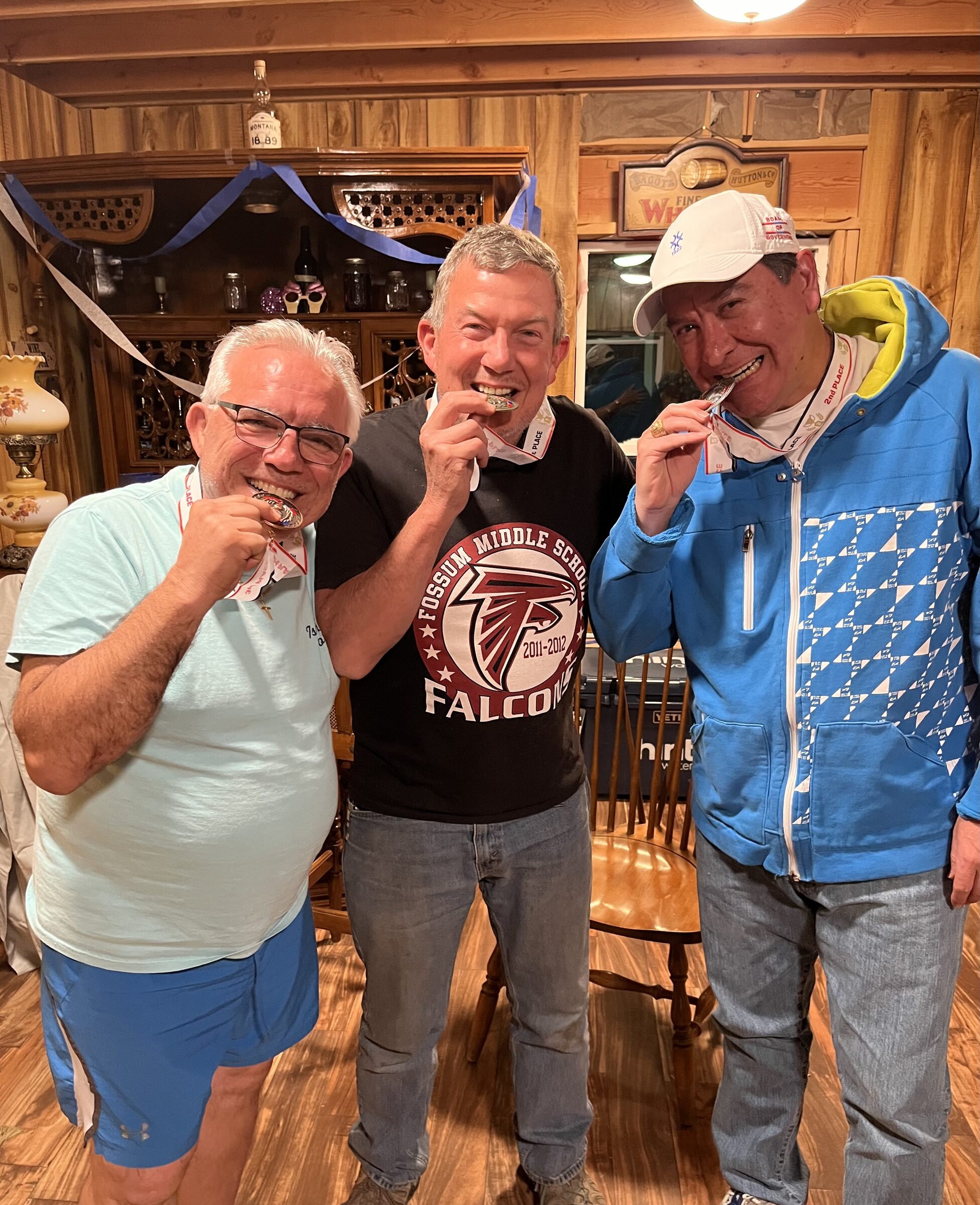 Three friends biting their medals after a friendly competition inside the Whiskey Ridge Saloon at Sweetwater Ranch