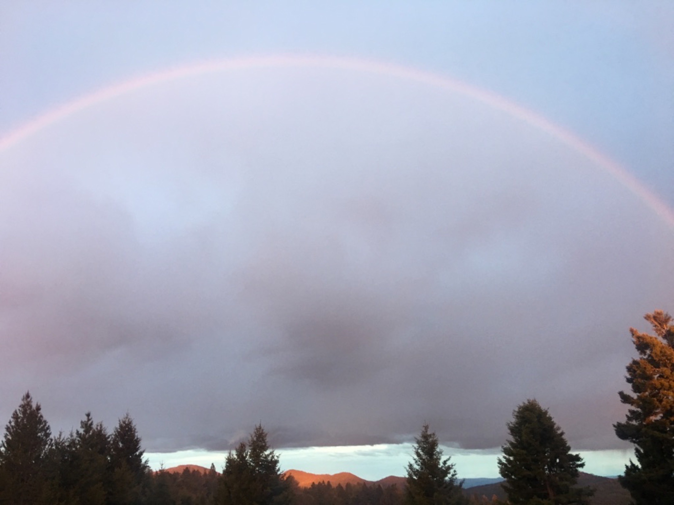A rainbow over mist and forested mountains at Sweetwater Ranch, Gold Creek, Montana — stillness and complete seclusion